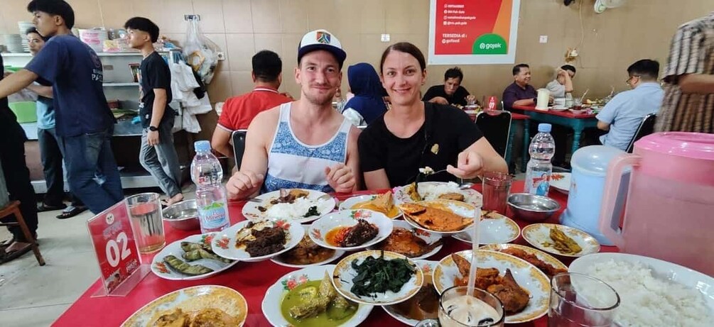 A restaurant with multiple tables filled with various dishes and people dining. 1