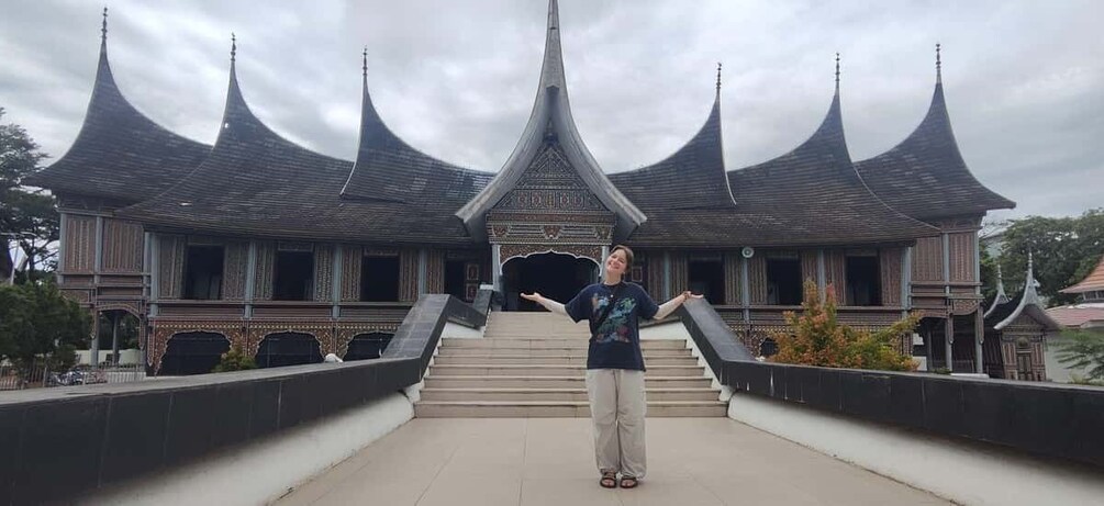 A person standing in front of a traditional building with multiple pointed roofs. 3
