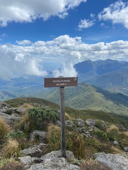 A signpost with 'PEDRA FURADA' and an altitude of 2,589 meters. 4
