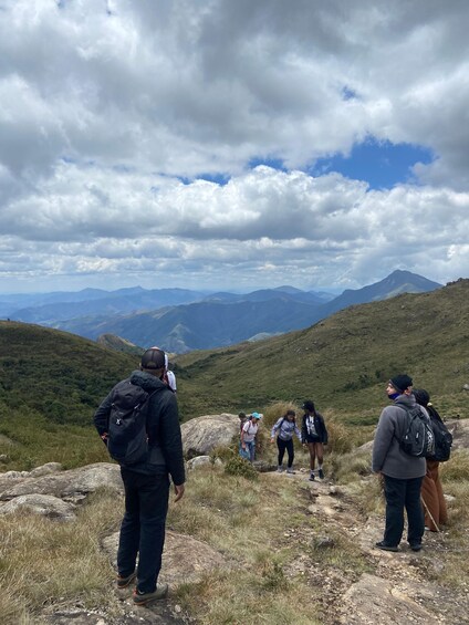 Hikers on a mountain trail with a view of distant mountains under a cloudy sky. 2