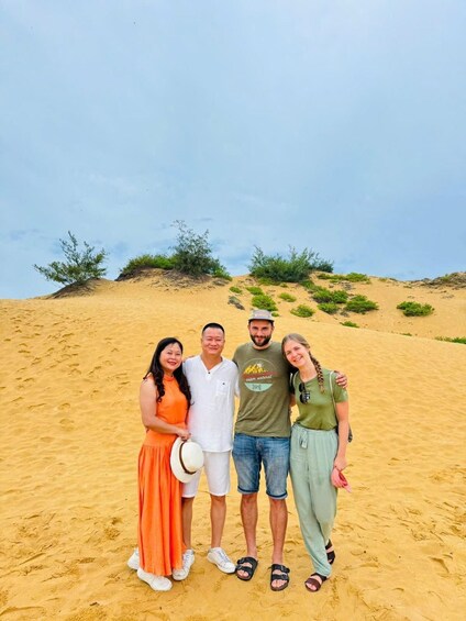 A group of people standing on a sandy beach with dunes in the background. 5