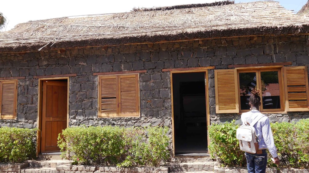 A stone building with wooden shutters and a thatched roof. 4