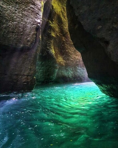 Une grotte avec une eau turquoise cristalline et des parois rocheuses recouvertes de mousse. 1