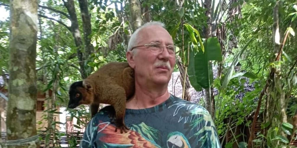 A person holding a monkey in a lush, green forest. 3