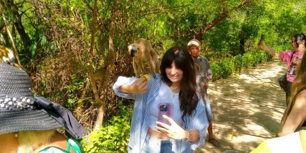 A person taking a selfie with a monkey in a forested area. 5
