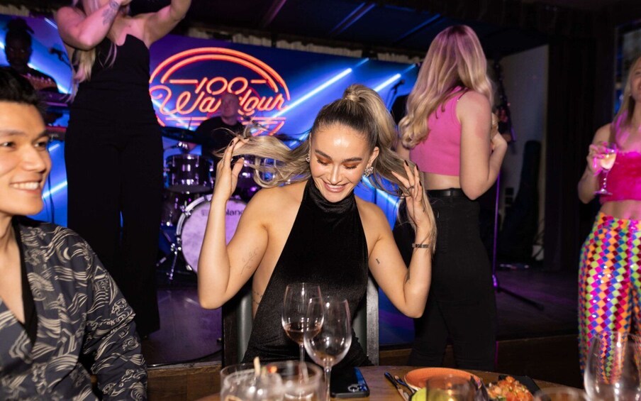 A person sitting at a table with a neon sign in the background. 5