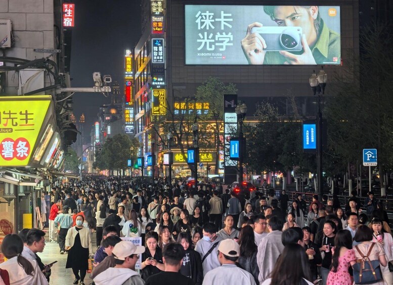 A crowded street at night with illuminated billboards and signs. 4