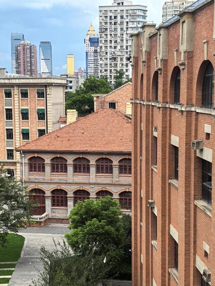 A historic building with arched windows and a red-tiled roof, surrounded by modern high-rise buildings. 5