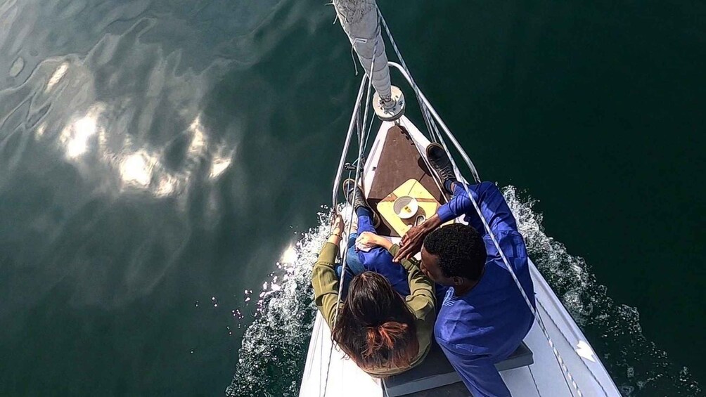 A boat with two people, one wearing a blue shirt and the other in a green shirt, on a body of water. 2