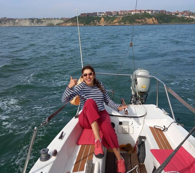 A person on a sailboat with a view of the sea and a coastline in the background. 5