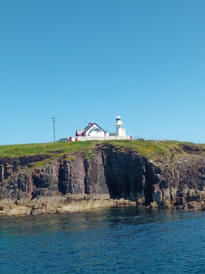 A lighthouse on a rocky cliff with a small building nearby. 5