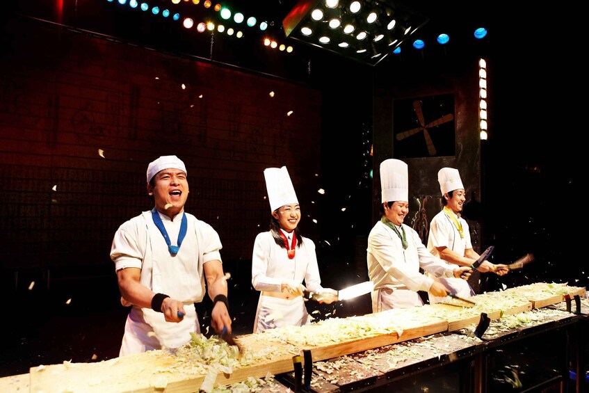 Chefs preparing food in a kitchen with a brick wall and colorful lights in the background. 1