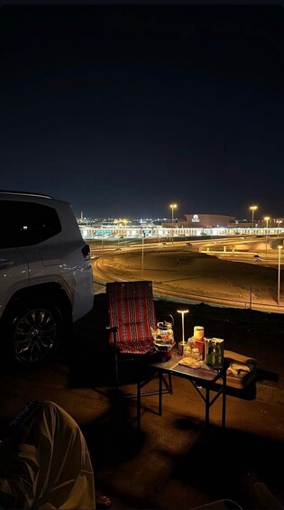 A white SUV parked on a dirt area with a chair and table set up for an outdoor meal. 5