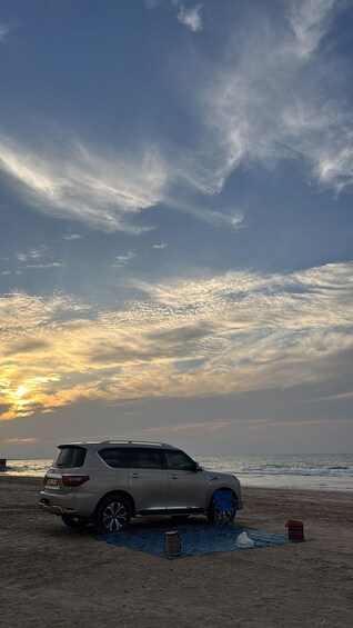 A car parked on a beach with a sunset in the background. 3