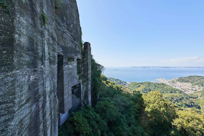 A cliff with a narrow passageway and a coastal city in the distance. 4
