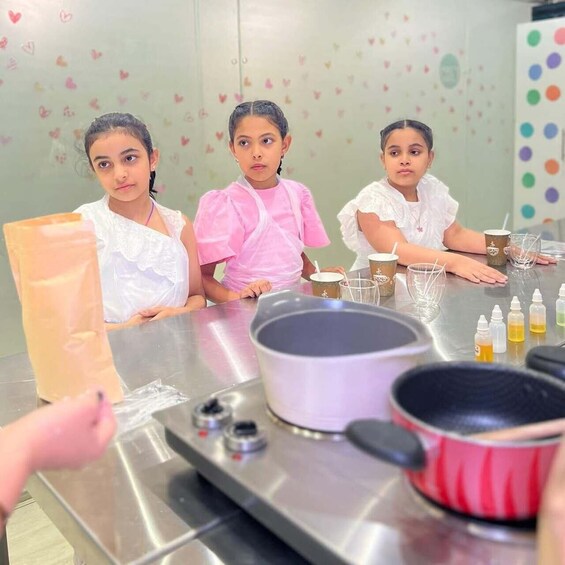 Three children at a table with a pot and bottles, possibly in a cooking or science activity. 5