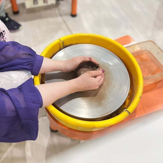 A person shaping a clay pot on a wheel. 1