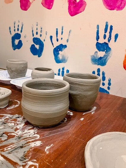 Pottery on a table with handprints in the background. 4
