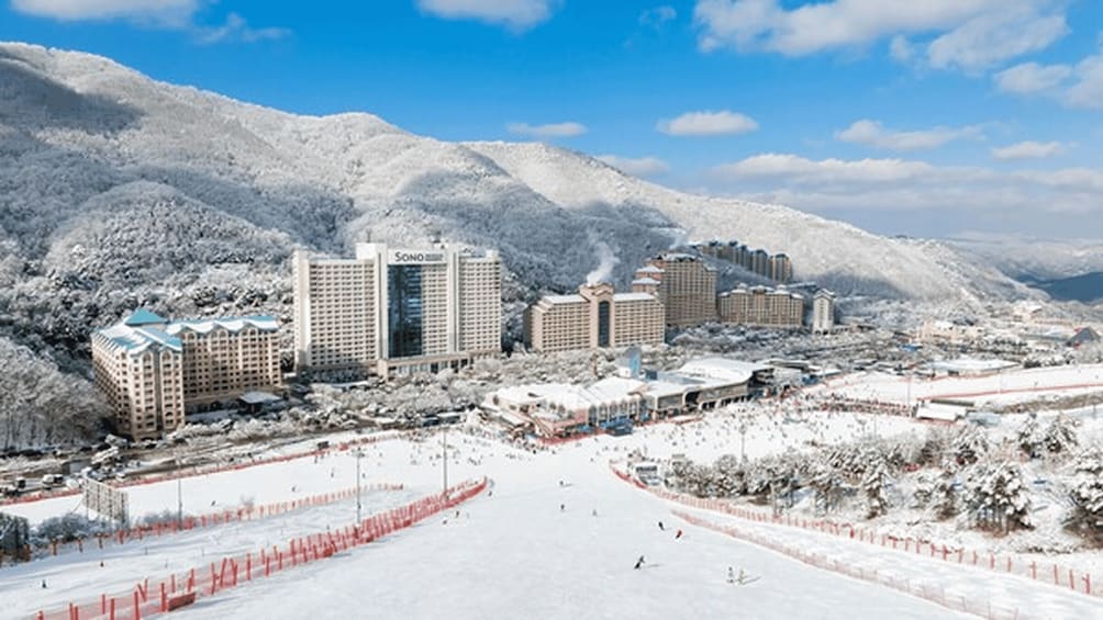 A snowy landscape with buildings and a ski slope. 3
