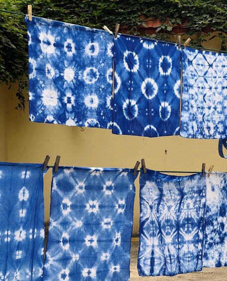 A series of blue and white patterned fabrics hanging on a line outdoors. 5
