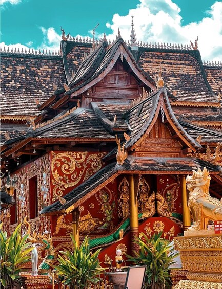 A traditional Thai temple with ornate decorations and a golden statue in the foreground. 1