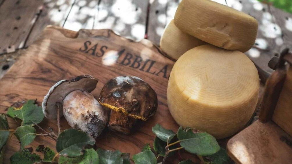 A wooden cutting board with the text 'SAS ABBILA' and several mushrooms. 4