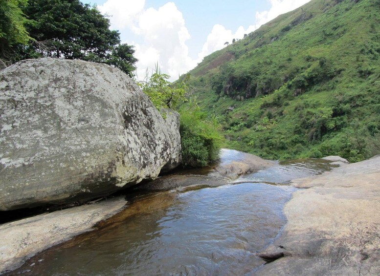 A river flowing through a valley with large rocks and lush greenery. 2