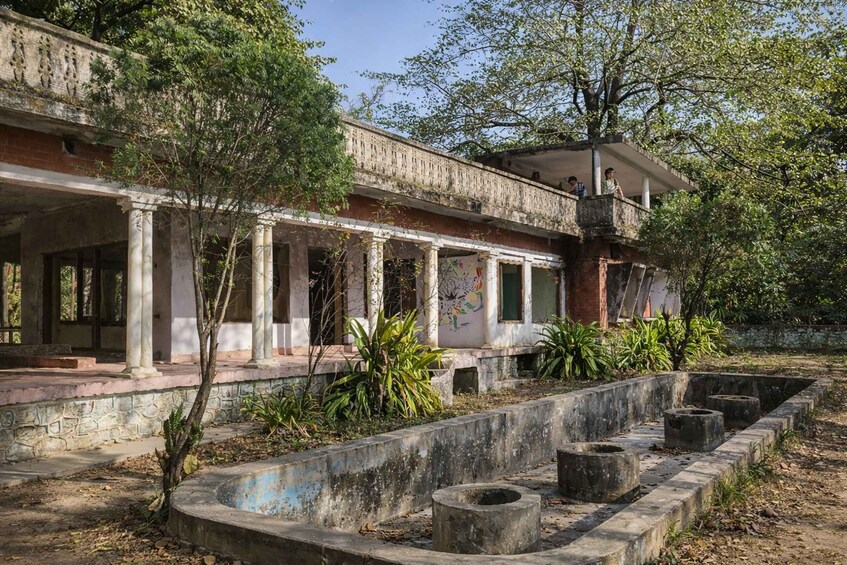 An abandoned building with columns, a courtyard, and trees. 5