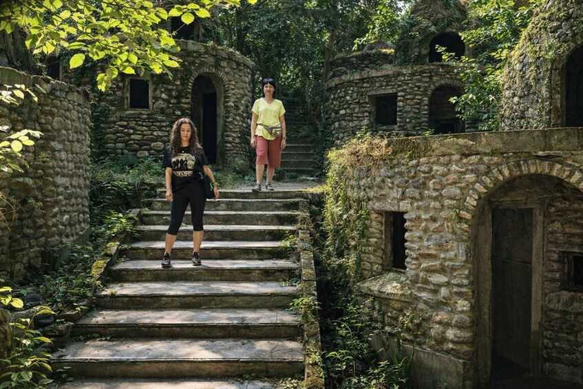 A woman in a black t-shirt and leggings walking up stone steps surrounded by greenery. 2