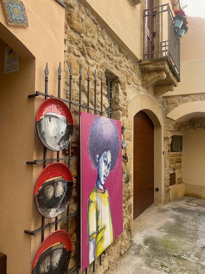 A street with a mural, metal plates, and a stone building. 3