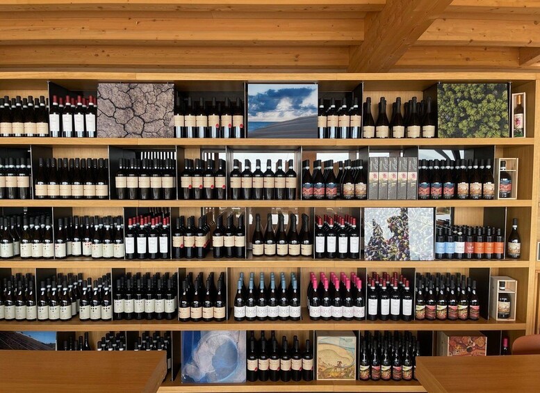 A wine cellar with multiple shelves of wine bottles, wooden beams, and artwork. 2