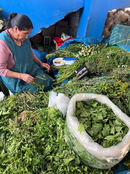 A person sorting through various leafy greens and herbs, with a large bag of greens in the foreground. 3