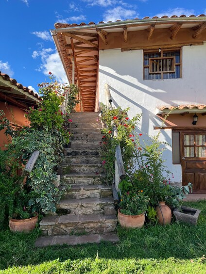 A rustic house with stone steps, wooden railings, and potted plants. 5