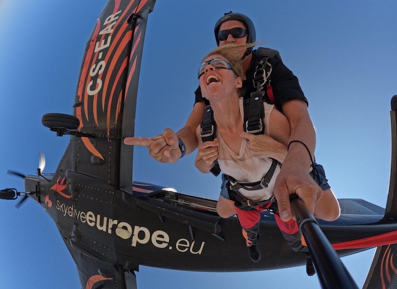 A person skydiving with a parachute, pointing at the sky. 1