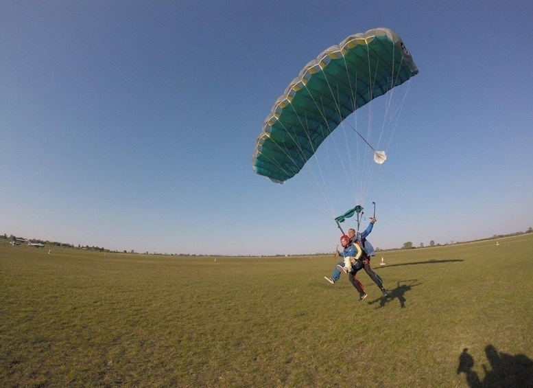 A person paragliding in a grassy field with a clear sky. 2