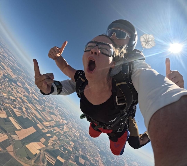 A person skydiving with another person holding their hand. 3