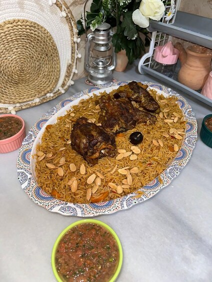 A plate of biryani with meat and almonds, a woven basket, a lantern, and a small bowl of sauce. 2