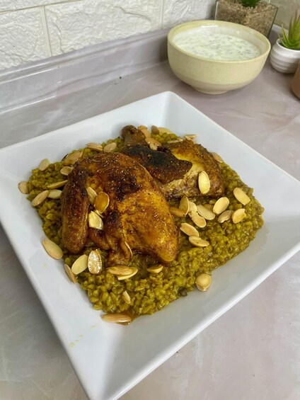 A plate of food with a roasted chicken and a green risotto-like dish, garnished with sliced almonds. 1