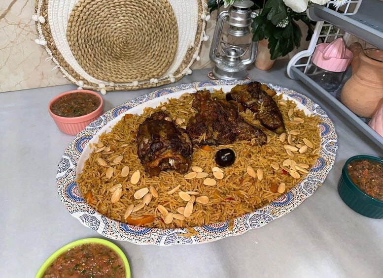 A plate of biryani with meat and almonds, accompanied by a bowl of sauce and a woven basket. 4