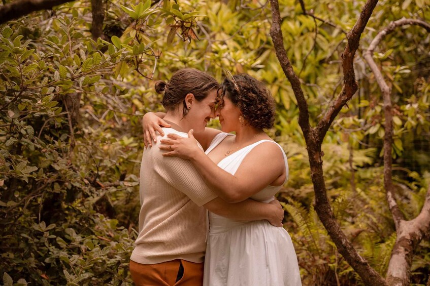 A couple embracing in a forested area with dense green foliage. 3
