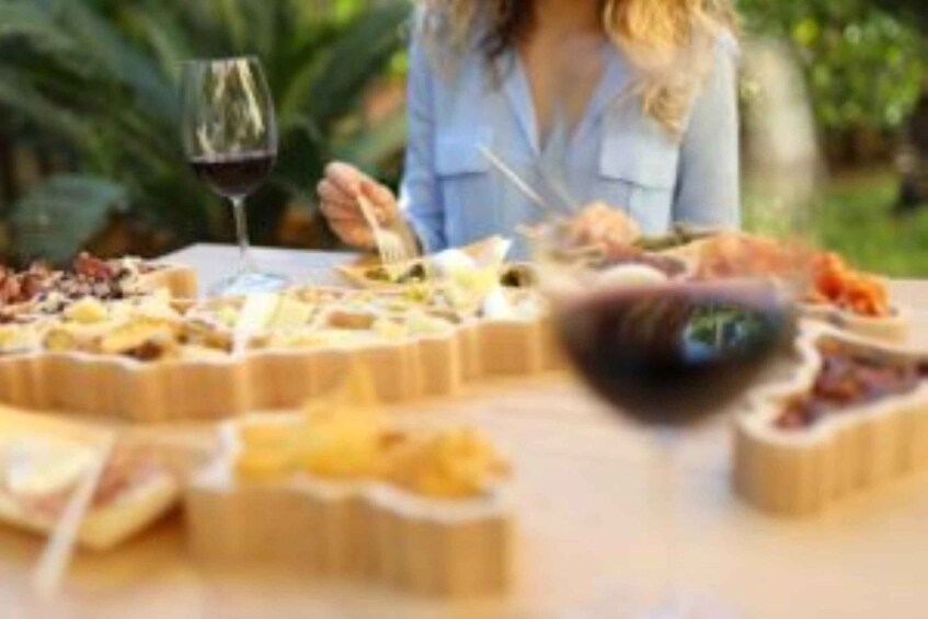 A woman dining outdoors with a variety of foods and a glass of wine on a table. 5