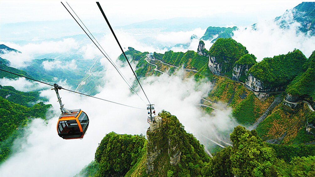 A cable car suspended over a lush green valley with misty mountains in the background. 3