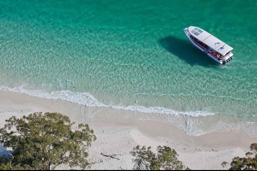 A boat on a clear turquoise sea with a sandy beach and sparse vegetation. 2