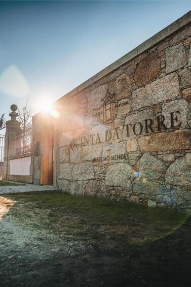 A stone wall with the inscription 'QUINTA DA TORRE' and 'MELLO MENDES' in a historical setting. 2