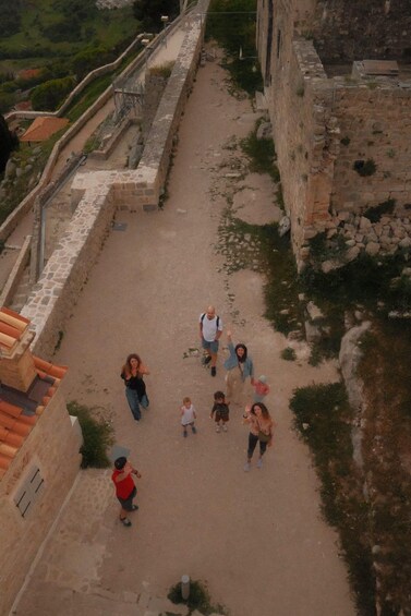 A group of people walking on a dirt path surrounded by ancient stone walls and ruins. 5