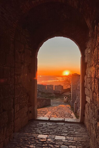An arched stone structure with a view of a sunset over a cityscape. 5