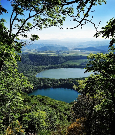 A lake surrounded by dense forest and rolling hills. 2