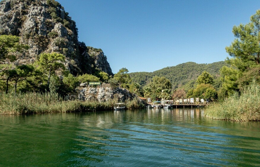 A river with boats, a rocky cliff, and a forested hill. 3