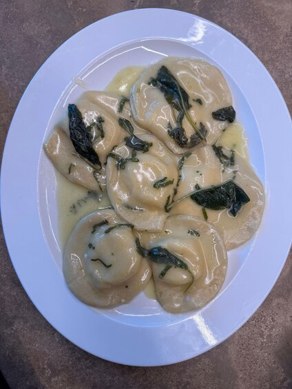 A plate of ravioli with a creamy sauce and herbs. 2
