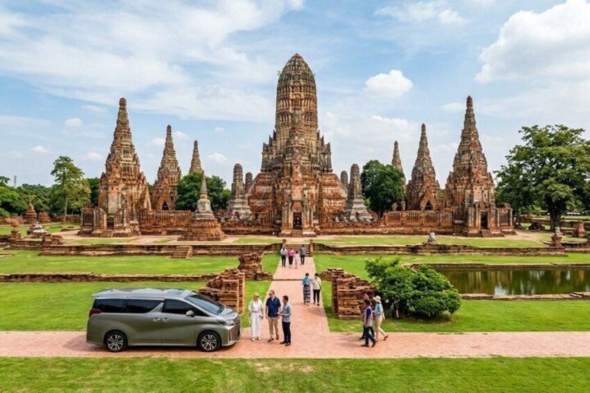 A temple complex with multiple structures, a paved pathway, and a parked car. 1